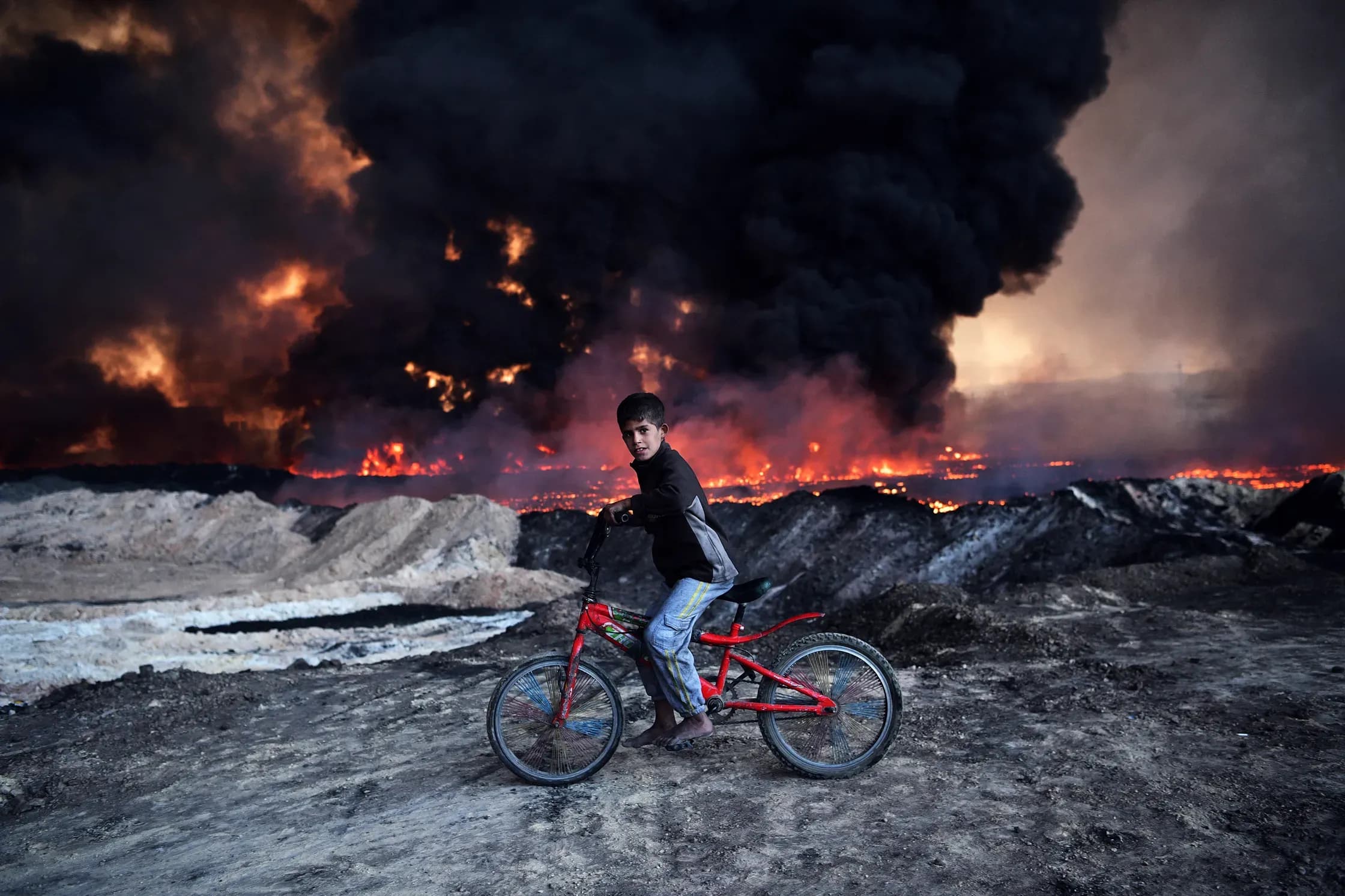 A boy passes an oil field set aflame by retreating ISIS fighters ahead of the Mosul offensive in Qayyarah, Iraq. CARL COURT/GETTY IMAGES